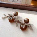 Primo piano di orecchini vintage a cuore in ambra con fiocco d'argento e perno marmorizzato. - Marrone