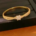 Detailaufnahme eines 18K vergoldeten Armbands mit funkelnder Zirkonia-Blume - Überkreuzter Gewickelter Blumenstil / Gold