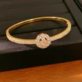 Detailansicht eines 18K vergoldeten Armreifs mit funkelndem Zirkonia-Blütencluster - Ovaler Blumen-Stil / Gold