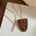 Nahaufnahme eines minimalistischen Lederanhängers mit Leopardenmuster an brauner Kordel - Halskette / Brauner Leopard