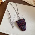 Minimalistische Halskette mit Leopardenmuster-Anhänger und brauner Kordel auf Buchstütze - Halskette / Weinrot-Schwarz Leopard