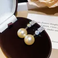 Primo piano di eleganti orecchini con perle dorate e accenti geometrici in zirconi - Perno Argento-Perla Bianca