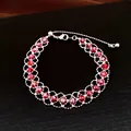 Detailansicht eines geflochtenen Silberarmbandes mit facettierten roten Kristallperlen - Armband - Silber / Rot