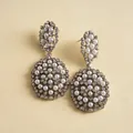 Gros plan de boucles d'oreilles argentées élégantes avec des grappes de perles et strass. - Argent