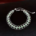 Detaillierte Makroansicht eines silbernen Netzarmbands mit funkelnden grünen Perlen. - Armband - Silber / Grün