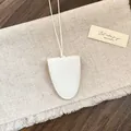 Detail van witte kiezellederen brilhouder hanger in de vorm van een bel - Wit