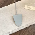 Detailopname van een saliegroene kiezellederen brillenhouder hanger voor ketting. - Grijs