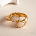 Gros plan d'un bracelet vintage doré avec pierres en résine marbrée et texture - Blanc