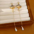 Detailweergave van elegante zirkonia bloemenoorbellen met druppelparels - Goud