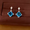 Nahaufnahme eleganter blauer Zirkon-Ohrringe in Rautenform auf braunem Samt - Silber Nadel Ohrringe / Silber-Blau