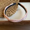 Detailansicht eines rosa gepunkteten, gedrehten Stoff-Stirnbands mit rutschfesten Zähnen - Rosa