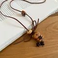 Close-up of a vintage wooden bear and star pendant on a brown cord necklace. - Bear (3#)