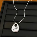 Detail view of matte silver oval pendant necklace with dotted pattern on black tray - Oval Pendant / Silver
