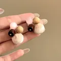 Detail view of autumn stud earrings with wood beads and pink cat-eye stones in hand. - Patchwork Style (Silver Needle) / Pink