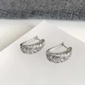 Detailansicht von 18k weißvergoldeten geometrischen Creolen mit Zirkonia-Steinen. - Silber