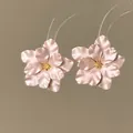 Elegante rosa Blumenohrstecker mit goldener Mitte auf klaren Kunststoff-Displayständern. - Blumenform / Rosa und Gold