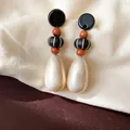 Detailed macro view of vintage water drop earrings with wooden beads and cream pearls. - Black-White