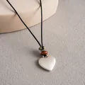 Gros plan d'un pendentif en céramique en forme de cœur sur un cordon noir ethnique - Pendentif cœur