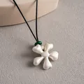 Détail d'un élégant collier à pendentif fleur en céramique blanche avec perle - Pendentif Fleur