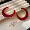 Nahaufnahme roter C-förmiger Creolen mit goldenen Strukturrändern auf Display - Großer C-Form Stil / Gold-Rot