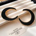 Detailaufnahme der übergroßen C-förmigen Creolen mit schwarzem Inlay und Goldrand. - Großer C-Form Stil / Gold-Schwarz