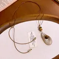 Detailansicht eines Vintage-Tigeraugen-Anhängers an einer braunen Lederkordelkette - Helles Kaffeegold & Braun