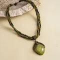 Detailopname van vintage boho-ketting met groene hars hanger en gevlochten koord - Gouden Groene Ruit Stijl