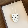 Detailopname van witte brillenclip-ketting met zwarte stippen op een canvas achtergrond - Brilhouder Ketting / Witte Stippen