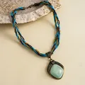 Gedetailleerde weergave van een gevlochten ketting in vintage stijl met een turquoise hanger - Gouden Blauwe Ruit Stijl