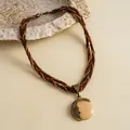 Detailopname van vintage gevlochten halsketting met gemarmerde hars hanger en strass-steentjes - Gouden Bruine Ronde Stijl