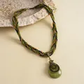 Detail van een vintage ketting met groene druppelhanger en een mooie gevlochten band - Gouden Groene Druppel Stijl