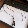 Primo piano del pendente orso in resina nera con perla in legno e fiocco. - Collana / Argento-Nero