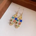 Gros plan de boucles d'oreilles ovales géométriques avec strass colorés et finition dorée - Crochet d'Oreille Géométrique / Or-Multicolore