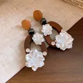 Nahaufnahme von Vintage-Holzohrringen mit weißen Blumenanhängern und Kristallen - Kaffee-Weiß