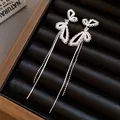 Detailed macro view of silver butterfly tassel earrings with delicate white pearl accents - Butterfly Tassel Stud / Silver
