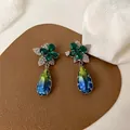 Nahaufnahme von tropfenförmigen Ohrringen mit grünem Blumendesign und Farbverlauf - Grün