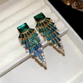 Vue détaillée des boucles d'oreilles en éventail avec cristaux vert émeraude et bleus - Vert