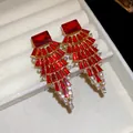 Vue détaillée d'élégantes boucles d'oreilles pendantes rouges en éventail avec strass - Rouge