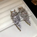 Détail rapproché de boucles d'oreilles scintillantes avec cristaux carrés et en éventail. - Argent