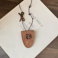 Detail view of a brown faux leather glasses holder necklace with leopard cat charm. - Cat Style / Brown