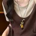 Close-up of vintage wooden acorn pendant necklace with rustic leaf details on brown cord - Black Accessory Decoration / Brown