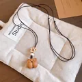 Gros plan d'un collier vintage avec pendentif ours en bois et détail de fleur perlée - Ours / Marron