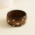 Detail view of a vintage dark wood bangle featuring geometric silver-tone studs. - Brown