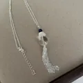 Detail einer Halskette mit Quastenanhänger, klaren und blauen Perlen auf einer Silberkette. - Halskette-Silber-Weiß-Glas