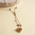 Macro detail of a retro gold heart necklace featuring pearls and filigree patterns. - Heart Bowknot Style / Gold