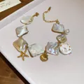 Eleganter goldfarbener Armreif mit unregelmäßigen Muschelstücken und Seestern-Anhängern - Irregular Shell Starfish Style / Gold