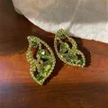Detailansicht eleganter grüner Strass-Ohrringe in Schmetterlingsform auf Holzoberfläche - Silberner Ohrstecker - Gold - Grün