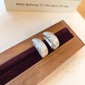Detailopname van geometrische zilveren oorbellen met zirkonia op een houten houder - Zilver