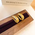Detailopname van vintage gouden oorringen met geometrische textuur en zirkoon - Goud