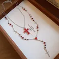 Détail d'un collier de perles avec croix en résine rouge et breloques argentées - Style Deux Pièces / Argent avec rouge